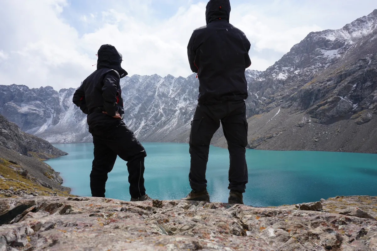 Claude Bauer und Daniel Aepli unterwegs in den Bergen vor einem See.